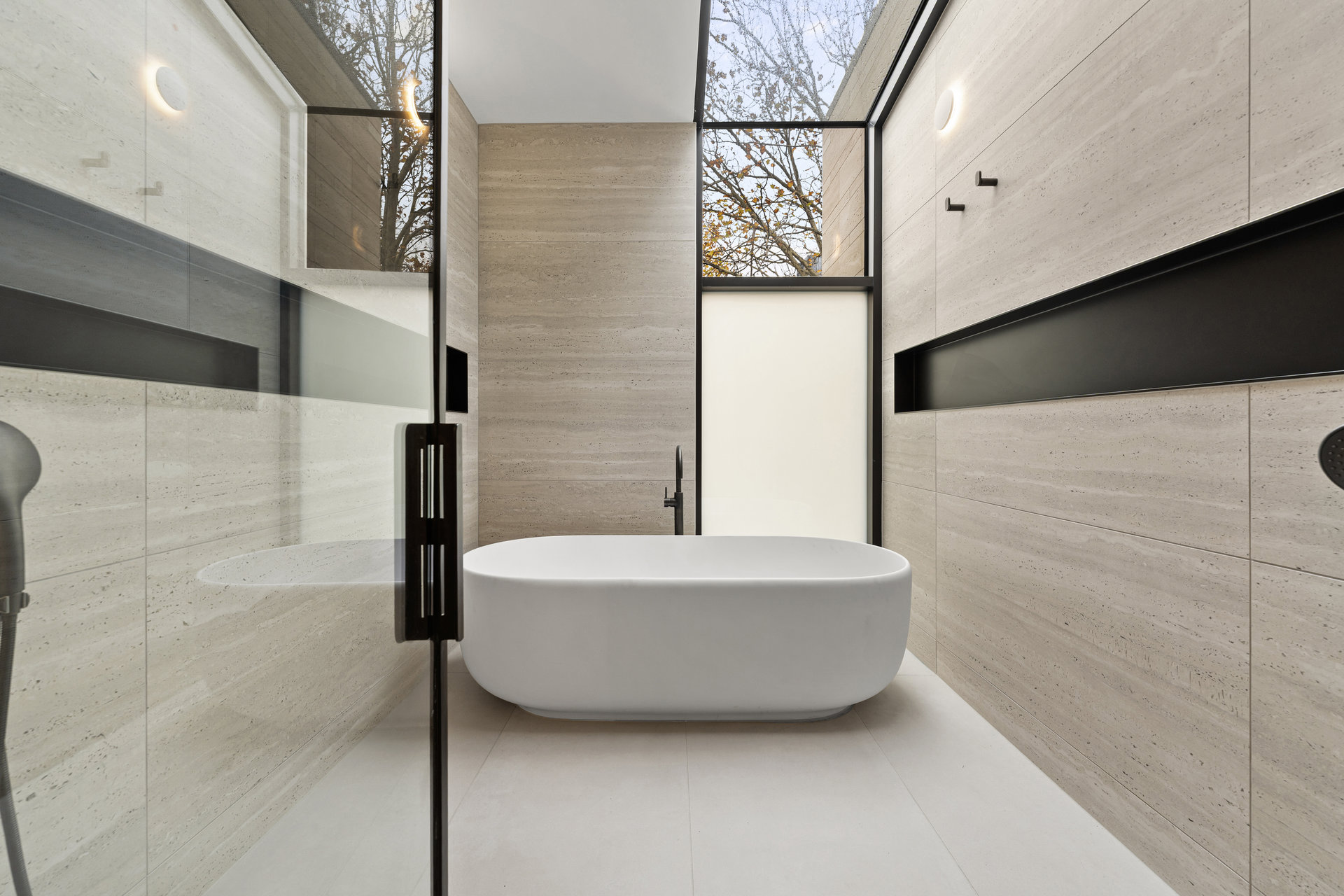 Travertine tiled bathroom with freestanding bath